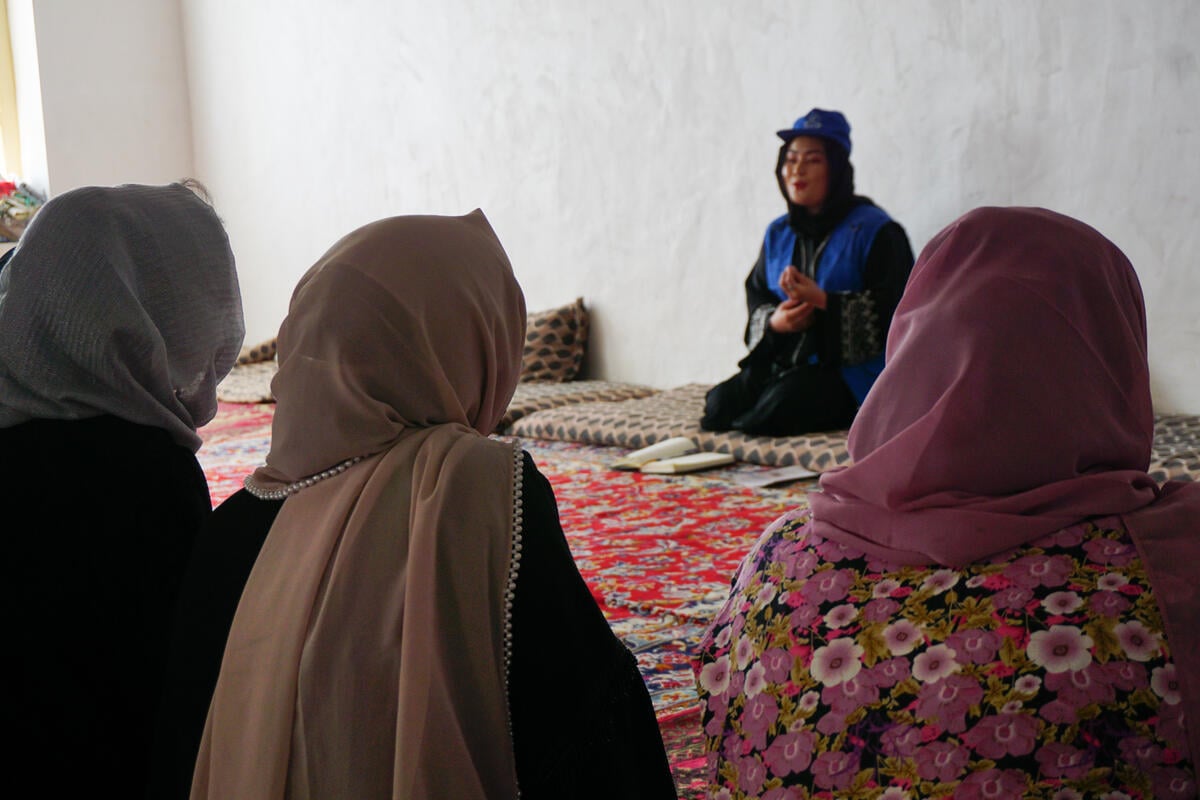 Un grupo de mujeres conversando sentadas en alfombras.