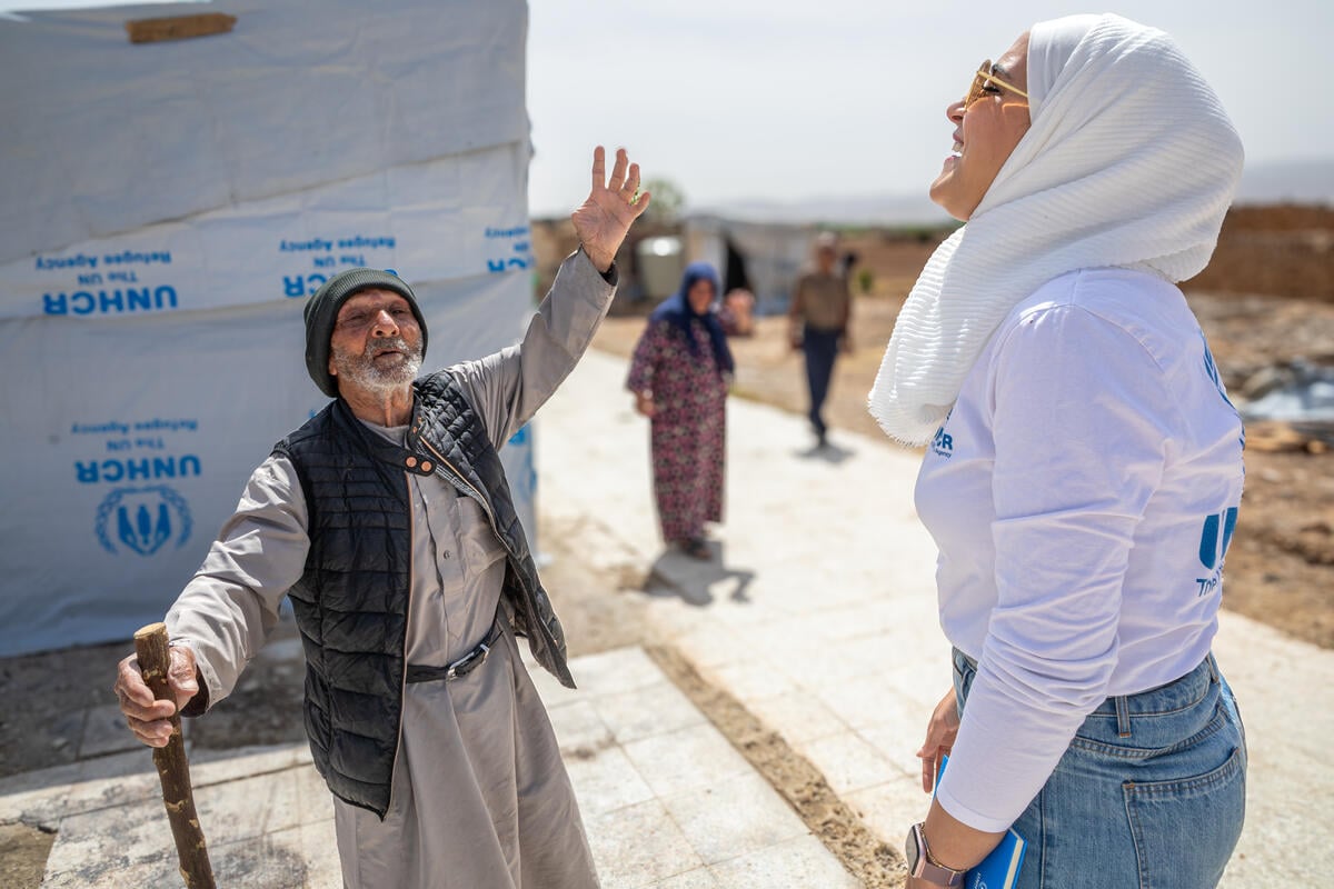 Jassim hablando con la asociada de protección de ACNUR Lujain Hasan fuera de la tienda de campaña donde vive con su familia, en el pueblo de Al-Nahryieh, en la gobernación de Homs, Siria.