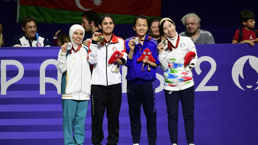 Cuatro mujeres posan juntas con medallas colgadas al cuello.
