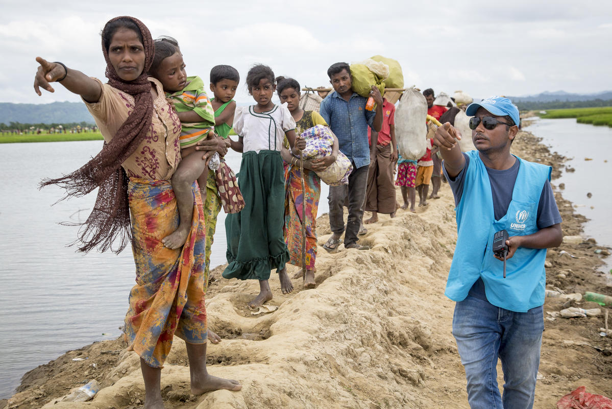 Rohingya arrivals at transit centre Una trabajadora de ACNUR le indica a un grupo de personas rohingyas refugiadas dónde se encuentra el centro de tránsito.