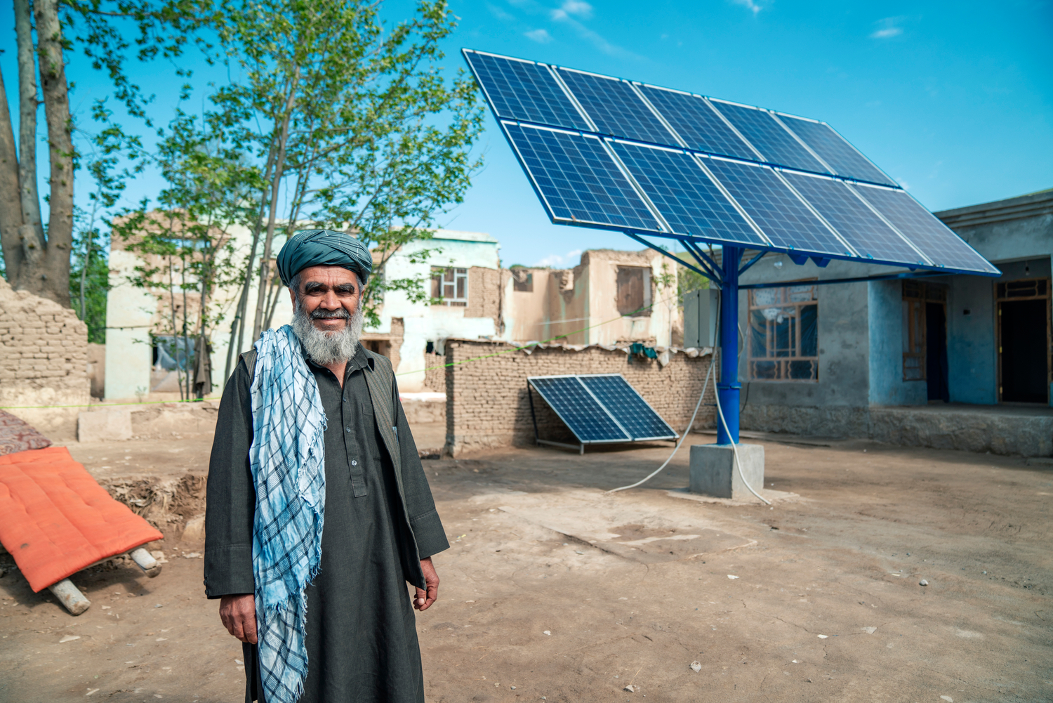 Un hombre con barba y turbante frente a un gran panel solar.