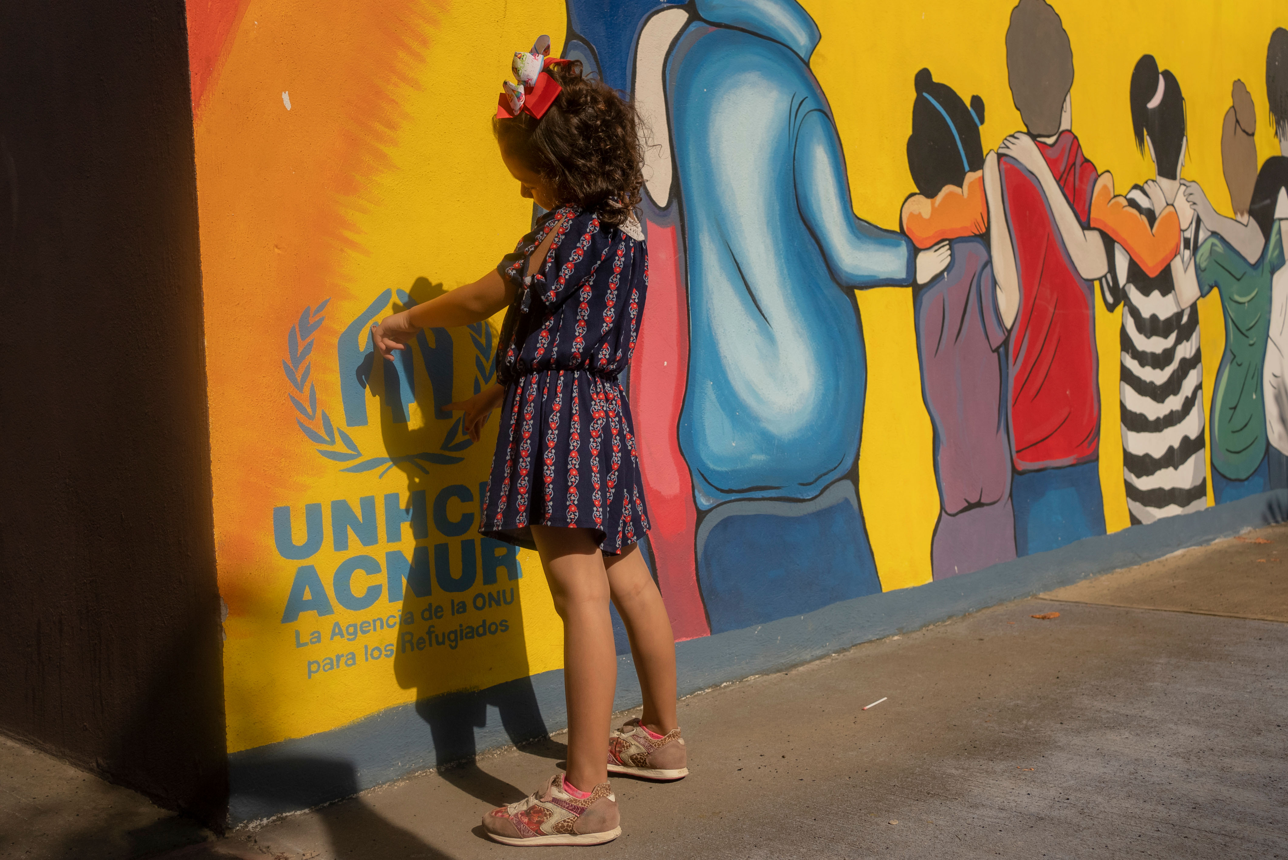 Una niña de espaldas hacia una pared de colores