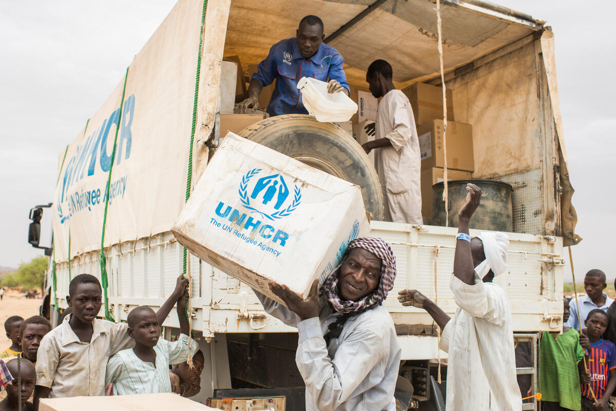 Un grupo de hombres descarga suministros de ACNUR de un camión en Chad