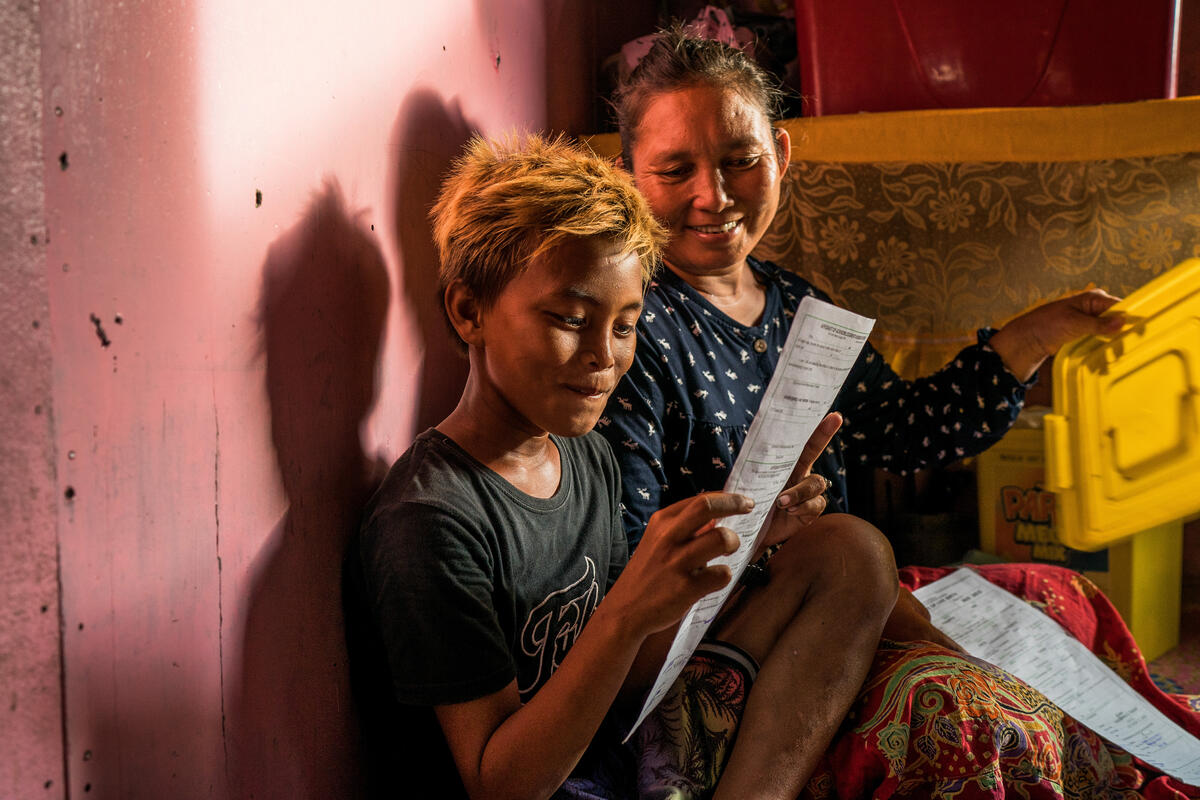Un joven filipino sostiene alegremente su certificado de nacimiento; a lado suyo, una mujer que comparte su alegría por contar finalmente con un documento de identidad