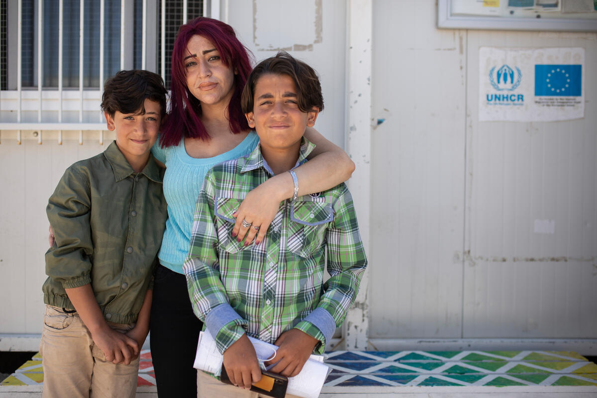 Una madre abraza a sus dos hijos; las tres personas miran fijamente a la cámara.