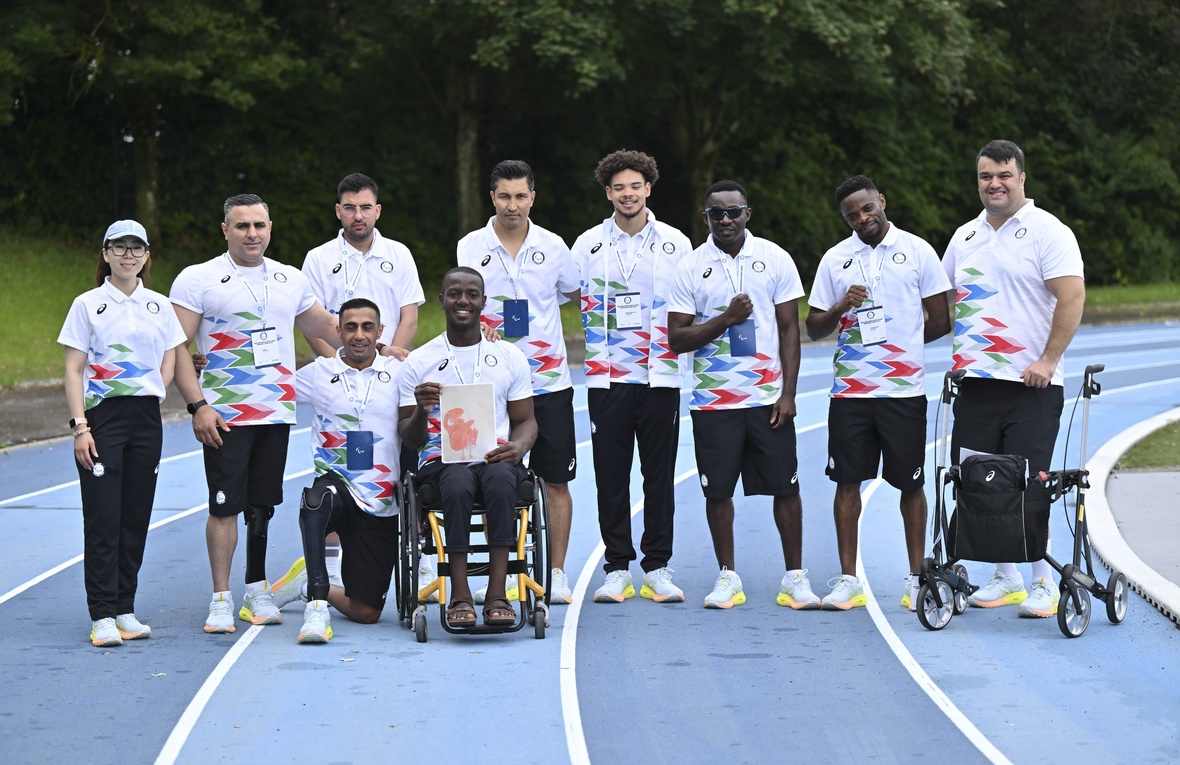 Atletas con uniformes a juego posan para una foto grupal en una pista de atletismo.