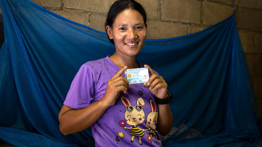 Una mujer con un documento de identidad en ambas manos sonríe a la cámara